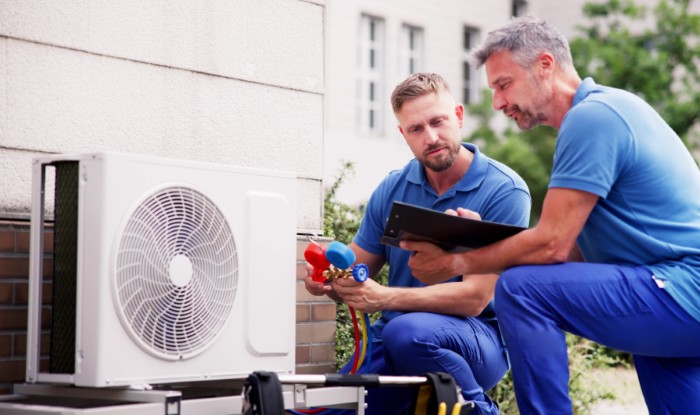 HVAC technicians reviewing an outdoor air conditioning unit in Brigham City, UT