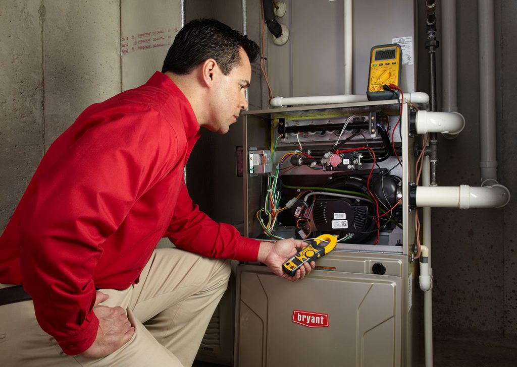 Heating and air conditioning technician servicing an indoor furnace in Brigham City, UT