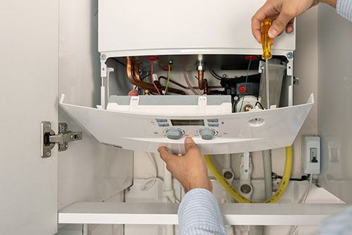HVAC technician repairing an indoor boiler in Brigham City