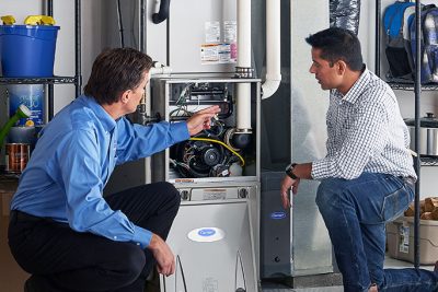 HVAC technician explaining furnace repair and maintenance to a homeowner in Brigham City, UT