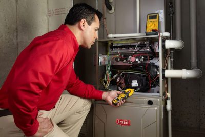 Heating and air conditioning technician servicing an indoor furnace in Brigham City, UT